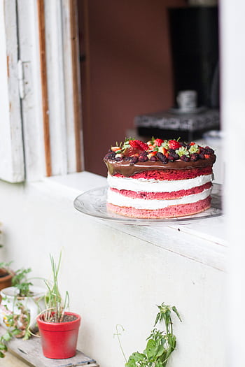 Enticing three-layer chocolate cake with strawberries and cream icing in a cozy setting. HD phone wallpaper