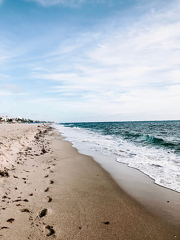 A serene beach with gentle ocean waves under a bright blue sky, perfect for a summer vacation. HD phone wallpaper