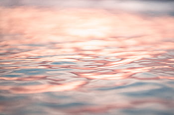 Close-up of tranquil ocean waves reflecting pink sunset hues, offering a peaceful and que scene. HD wallpaper