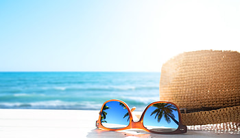 Palm trees reflect off of sunglasses placed by a hat on the beach, blue, sand, coast, beach, vacation, shore, summer, sunglasses, sky, sun, water, ocean, palm trees, hat HD wallpaper