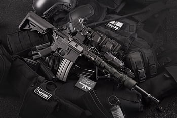 Close-up of tactical military gear including a rifle, radio, and vest on a dark background. HD wallpaper