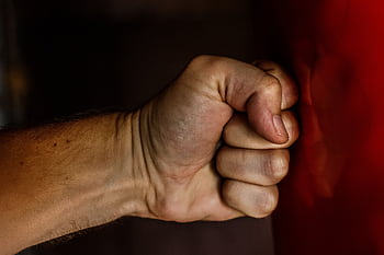 A detailed close-up of a clenched fist striking a red surface showcasing strength. HD wallpaper