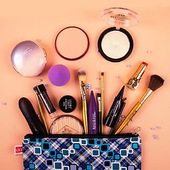A vibrant assortment of makeup tools and products stylishly arranged on a peach background. HD phone wallpaper