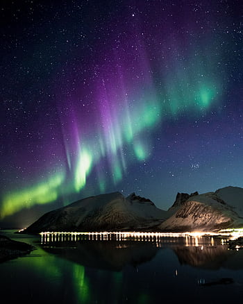 Captivating view of the Aurora Borealis dancing over snow-covered mountains reflecting on a serene lake. HD phone wallpaper
