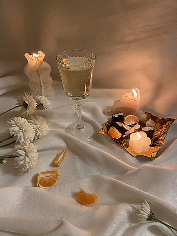 A cozy candlelit setup featuring wine, flowers, and dessert on draped fabric. HD phone wallpaper