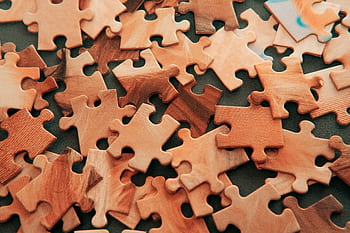 A close-up view of scattered wooden jigsaw puzzle pieces on a dark surface. HD wallpaper