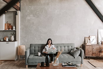 A woman working on a laptop in a stylish and cozy living room with modern decor. HD wallpaper