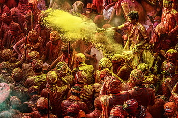 Crowd celebrating Holi festival with colorful powders in vibrant outdoor setting. HD wallpaper