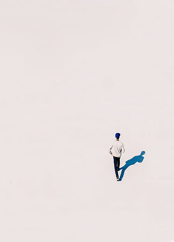 A single person walking in a minimalist setting casting a distinct shadow. HD phone wallpaper