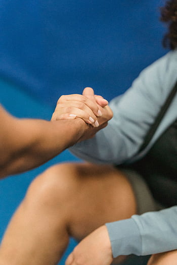 A close-up of a supportive handshake between two women in a gym setting, promoting wellness. HD phone wallpaper