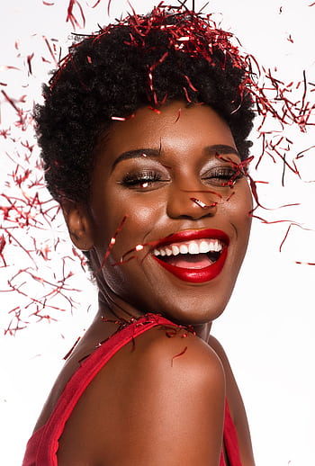 Radiant woman smiling amidst red confetti celebrating New Year's cheer. HD phone wallpaper