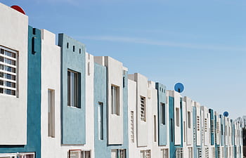Geometric blue and white facade of a modern apartment building under a clear sky. HD wallpaper