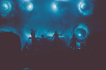Silhouetted band performing on a smoke-filled stage with dramatic lighting. HD wallpaper
