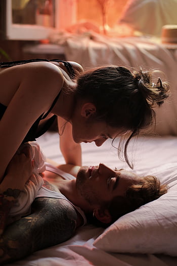 Couple sharing intimate moments in a softly lit, cozy bedroom. HD phone wallpaper