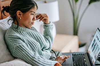 Young woman using laptop for online shopping while relaxing at home, showcasing casual digital lifestyle. HD wallpaper