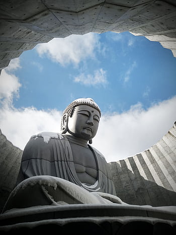 A serene Buddha statue covered in snow, set against a blue sky in Sapporo, Japan. HD phone wallpaper