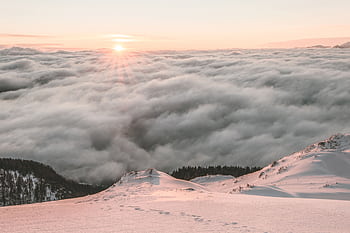 Breathtaking view of sunrise over a snow-covered mountain and a sea of clouds, capturing nature's serene beauty. HD wallpaper