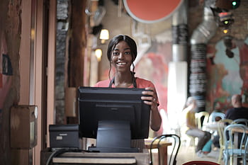 Cheerful café employee in a restaurant environment at a cash register. HD wallpaper