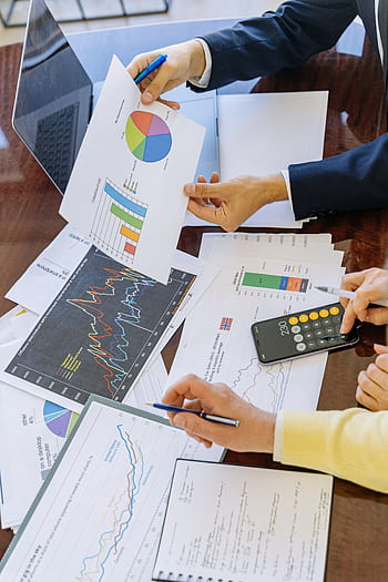 Business professionals analyzing financial charts and graphs during a meeting. HD phone wallpaper
