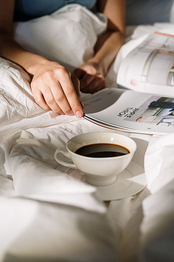 A serene morning scene with a cup of coffee and a magazine in bed, capturing tranquility. HD phone wallpaper