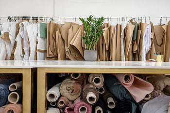 Interior of a fashion studio featuring fabric rolls and dress patterns on hangers. HD wallpaper