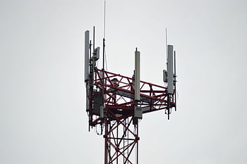 A red communication tower with antennas stands tall against a gray sky. HD wallpaper
