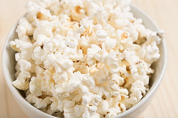 Close-up of freshly popped popcorn in a white bowl, perfect for a movie night snack. HD wallpaper