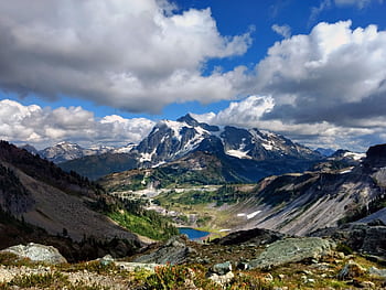 Stunning vista of Mount Shuksan with snow-capped peaks, lush valleys, and dramatic clouds. HD wallpaper