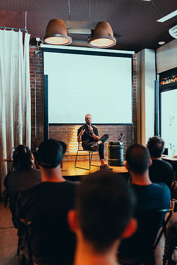 Speaker engages an audience during a business seminar in a modern conference room. HD phone wallpaper