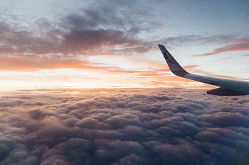 Captivating view from the airplane showcasing clouds and vibrant sunset hues, conveying the essence of air travel. HD wallpaper