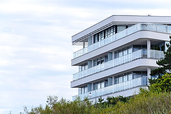 A contemporary apartment building with glass balconies and sleek design set against a clear sky. HD wallpaper