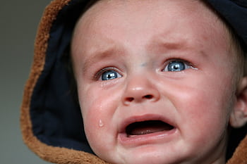 Emotional close-up of a baby in tears, highlighting raw emotion and vulnerability. HD wallpaper