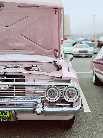 Front view of a pink vintage car with an open hood at an outdoor auto show. HD phone wallpaper