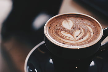 Warm mocha with heart-shaped latte art in a black ceramic cup on a saucer. HD wallpaper
