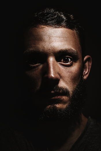 Close-up of a serious man with a beard in a dramatic shadowed portrait. HD phone wallpaper