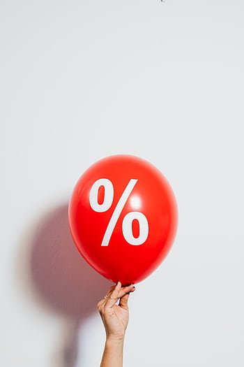 A red balloon with a percentage symbol held against a white background, symbolizing discounts and sales. HD phone wallpaper