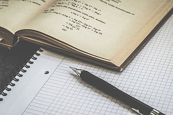 Mathematical study scene with open book, graph paper, and pen for learning and homework. HD wallpaper