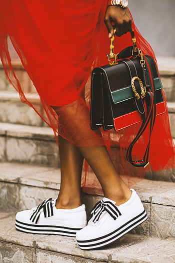 Elegant pose featuring modern sneakers and a chic designer handbag on stone steps. HD phone wallpaper