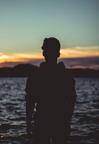 A silhouetted man stands by Lake Ozark during a beautiful sunset, creating a peaceful and serene scene. HD phone wallpaper