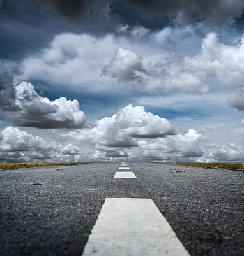 A straight road stretched toward a dramatic sky filled with fluffy clouds, creating a sense of journey. HD phone wallpaper