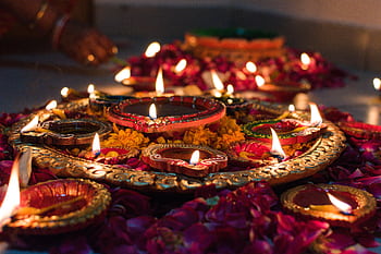 Beautifully lit traditional oil lamps (diyas) decorated with marigold flowers, celebrating Diwali in Jaipur, India. HD wallpaper