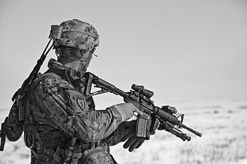 A soldier in military gear holding a rifle, captured in black and white. HD wallpaper