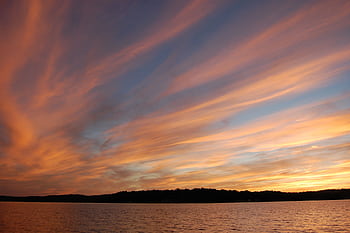 Beautiful sunset with orange and pink clouds over calm ocean waters, creating a serene seascape. HD wallpaper
