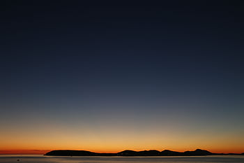 Beautiful sunset over an island silhouette with a colorful sky, perfect for nature and travel themes. HD wallpaper