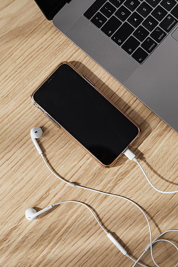 Modern workspace featuring a smart, laptop, and ears on a wooden table. HD phone wallpaper