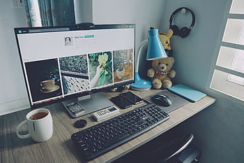 A tidy home office desk setup with a computer, keyboard, and personal items, creating a cozy work atmosphere. HD wallpaper