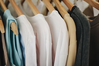 A selection of colorful clothes neatly hanging on wooden hangers in a retail store. HD wallpaper