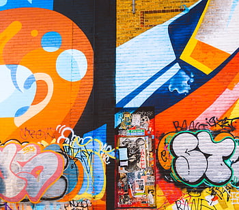 Colorful graffiti mural on a brick wall featuring abstract and bold designs. HD wallpaper