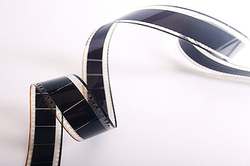 Close-up of a curled filmstrip against a white background, emphasizing vintage cinema. HD wallpaper
