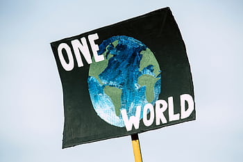 Close-up of a protest sign with Earth and 'One World' text, symbolizing climate change awareness. HD wallpaper